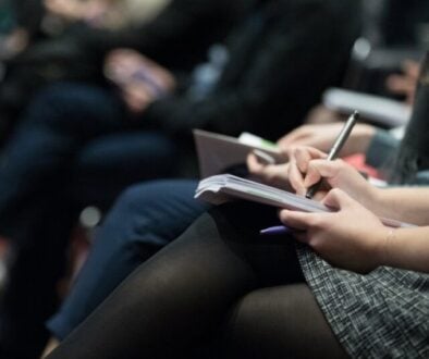 a woman writing in a notebook resting on her lap