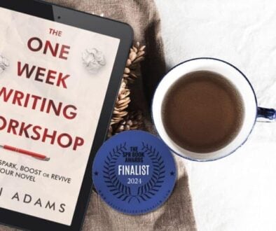 The One Week Writing Workshop book by Karin Adams on a tablet resting beside a coffee and a sticker proclaiming it to be a finalist in the SPR Book Awards 2024.