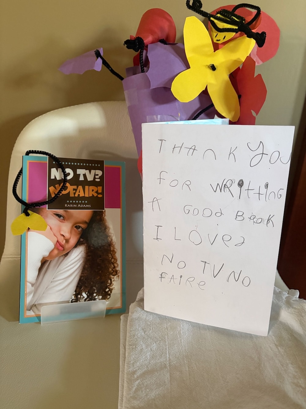 bouquet of construction paper flowers and a thank you note beside a children's book
